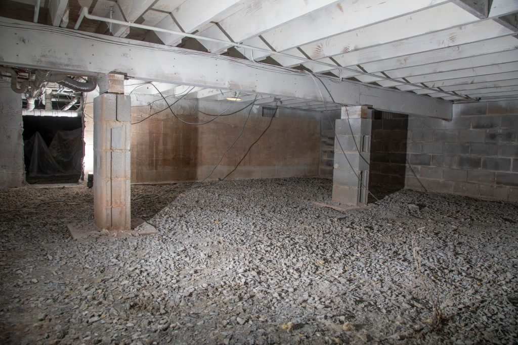 Basement prepared for insulation - concrete pillars and gravel over the floor